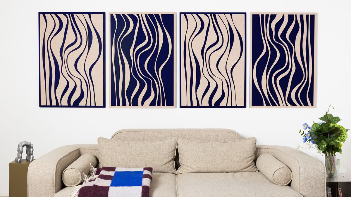 Four decorative soundproofing panels with abstract patterns mounted above a beige sofa in a modern living room interior.