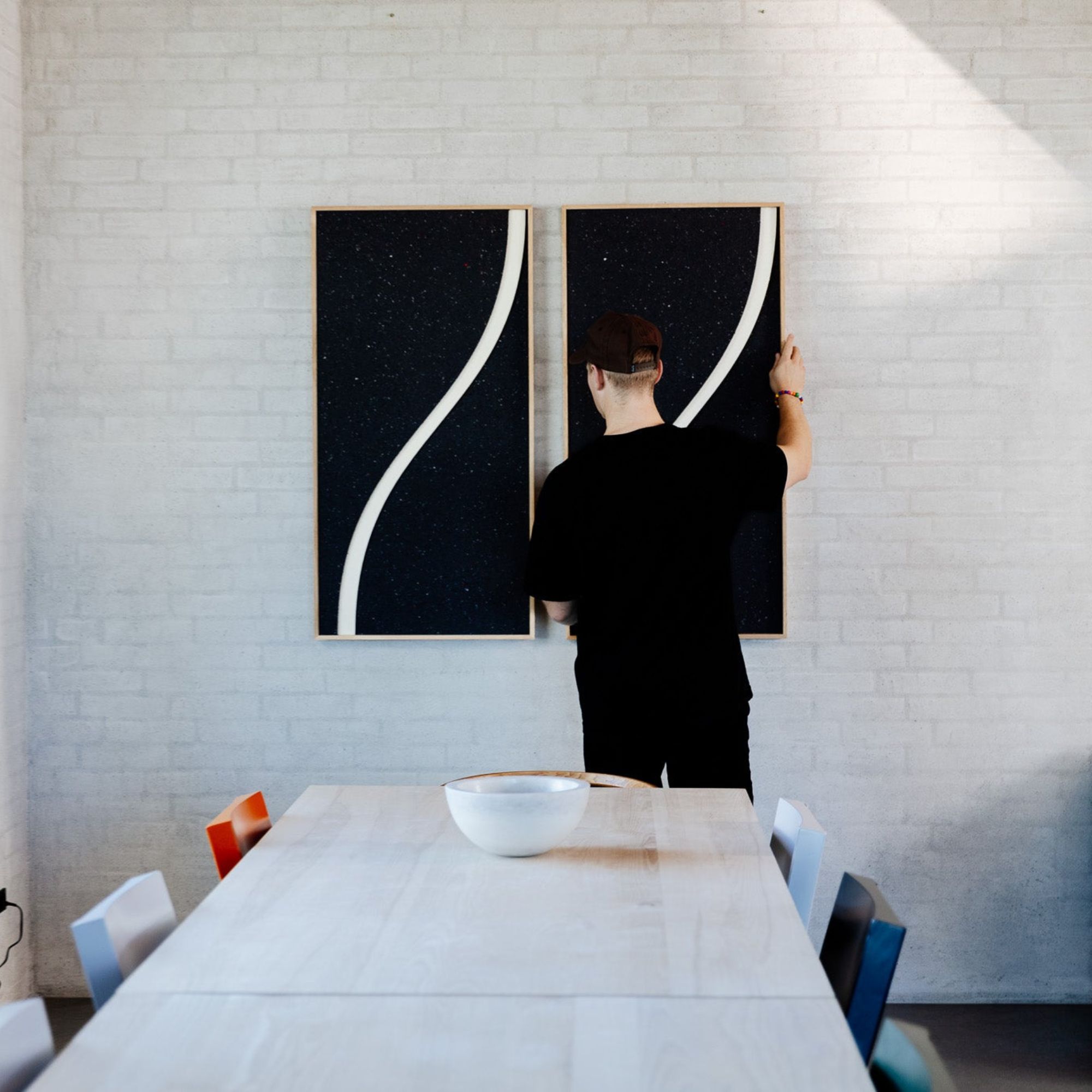 Man installing modern acoustic panels in a dining room to create visual interest and ensure good acoustics in a room.